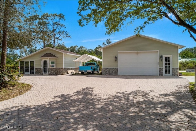 exterior space featuring decorative driveway, stone siding, and an outdoor structure