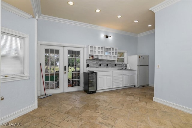 kitchen with baseboards, ornamental molding, freestanding refrigerator, open shelves, and a sink