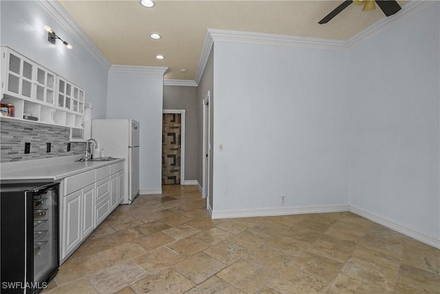 kitchen with tasteful backsplash, baseboards, wine cooler, freestanding refrigerator, and a sink