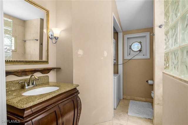 bathroom featuring baseboards, toilet, washer / clothes dryer, tile patterned flooring, and vanity