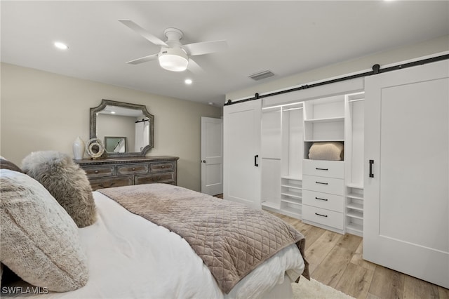 bedroom with a barn door, recessed lighting, visible vents, a ceiling fan, and light wood-type flooring