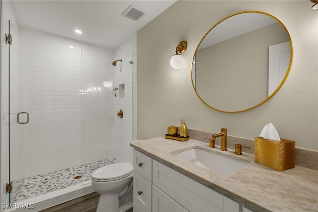 full bathroom featuring visible vents, toilet, wood finished floors, vanity, and a shower stall