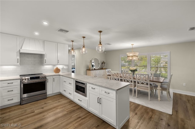 kitchen with stainless steel appliances, a peninsula, and white cabinetry