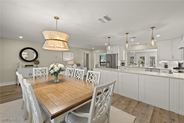 dining area with light wood finished floors, visible vents, and recessed lighting