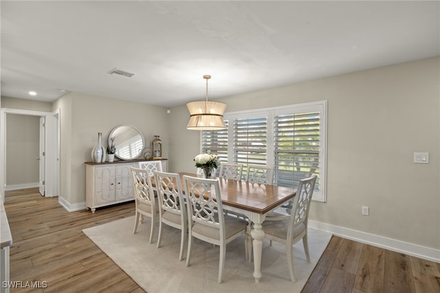 dining area with light wood-type flooring, visible vents, and baseboards