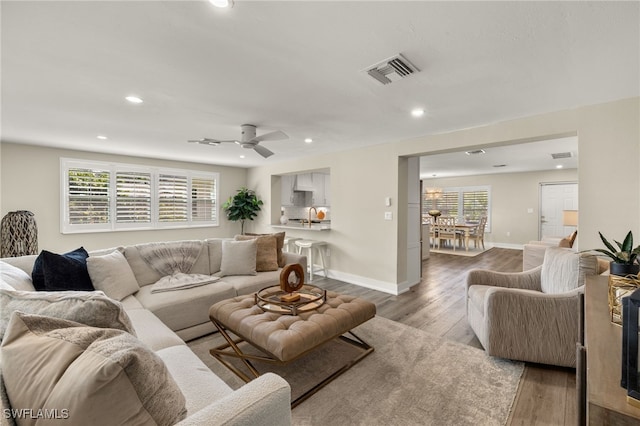 living room featuring recessed lighting, light wood-type flooring, visible vents, and baseboards