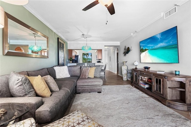 living area featuring baseboards, ornamental molding, visible vents, and a ceiling fan