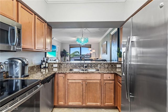 kitchen with appliances with stainless steel finishes, brown cabinets, a sink, and ornamental molding