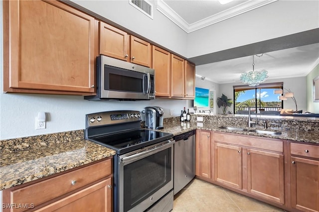 kitchen featuring dark stone countertops, crown molding, appliances with stainless steel finishes, and a sink