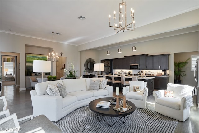 living room with a chandelier, wood finished floors, visible vents, and crown molding