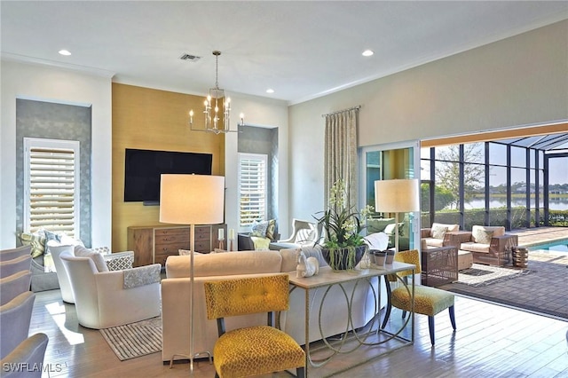 living room featuring a chandelier, plenty of natural light, wood finished floors, and visible vents