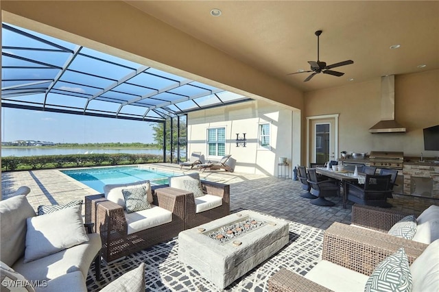 view of patio with an outdoor kitchen, an outdoor living space with a fire pit, area for grilling, glass enclosure, and a water view