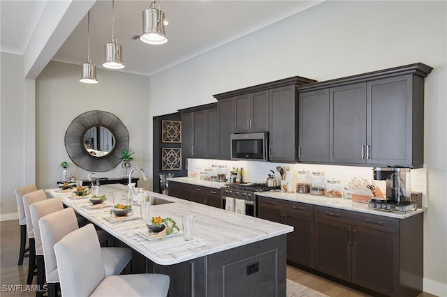 kitchen with light stone counters, a sink, ornamental molding, appliances with stainless steel finishes, and a kitchen bar