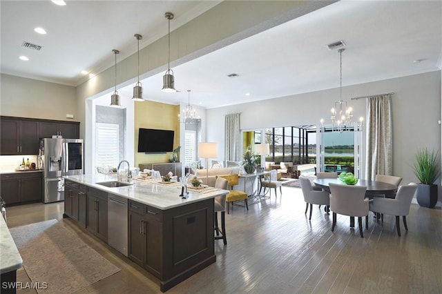 kitchen with stainless steel appliances, wood finished floors, a sink, and an inviting chandelier