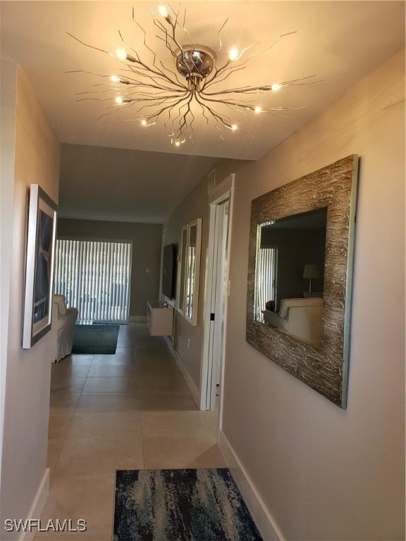 hall featuring tile patterned flooring and baseboards