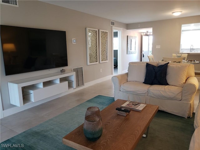 tiled living area featuring a sink, visible vents, and baseboards