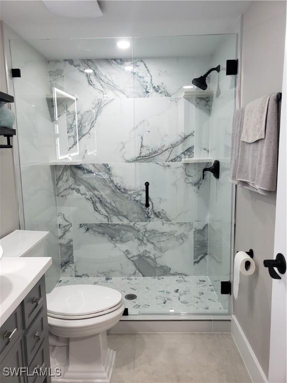 bathroom with toilet, a marble finish shower, and vanity