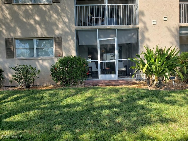 entrance to property with a yard and stucco siding