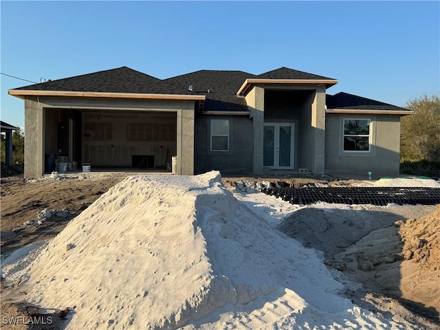 view of front of property with french doors, roof with shingles, an attached garage, and stucco siding