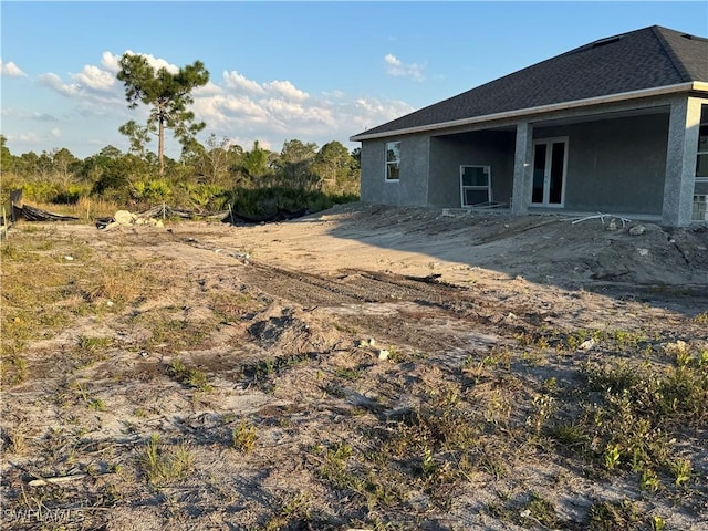 back of house with roof with shingles and stucco siding