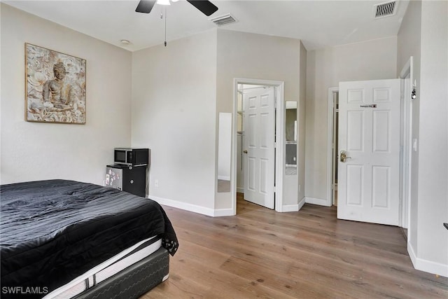 bedroom featuring a ceiling fan, visible vents, baseboards, and wood finished floors