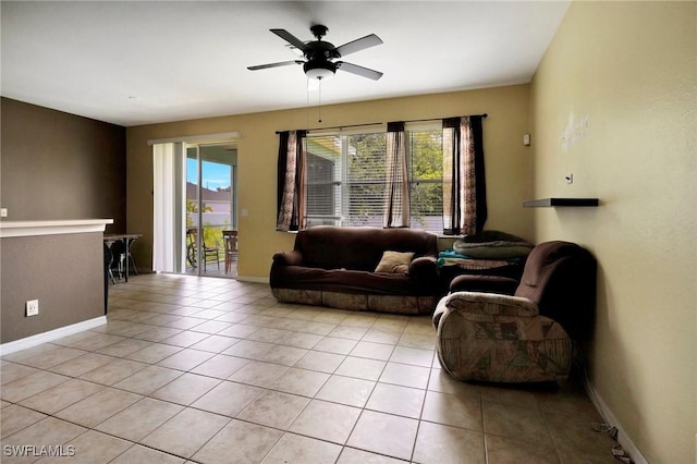 living room with light tile patterned floors, baseboards, and a ceiling fan