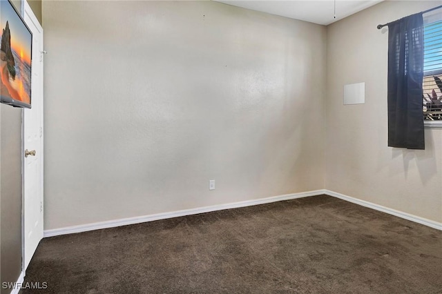 empty room featuring dark carpet and baseboards