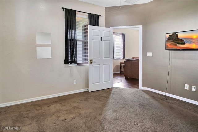 spare room with dark carpet and baseboards