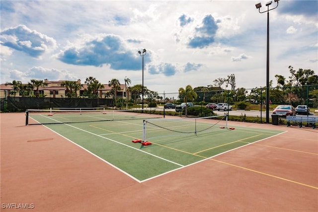 view of tennis court with community basketball court and fence