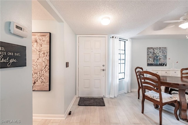 foyer with a textured ceiling, ceiling fan, light wood-type flooring, and baseboards