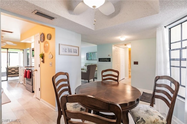 dining room with ceiling fan, a textured ceiling, visible vents, and baseboards