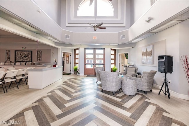 living area with visible vents, baseboards, ceiling fan, a high ceiling, and french doors