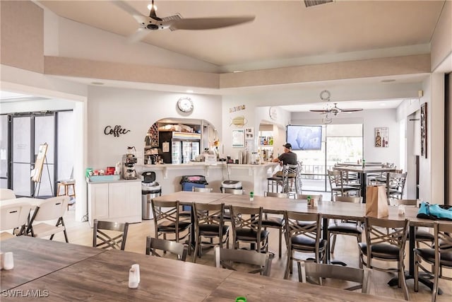 dining room featuring lofted ceiling, light wood-style floors, visible vents, and a ceiling fan