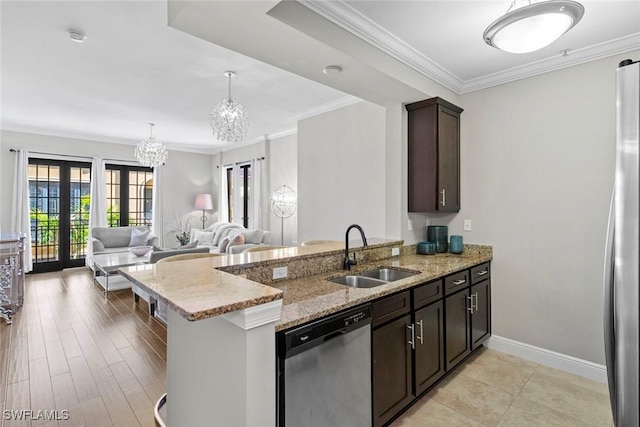 kitchen featuring light stone counters, dark brown cabinetry, a sink, appliances with stainless steel finishes, and an inviting chandelier