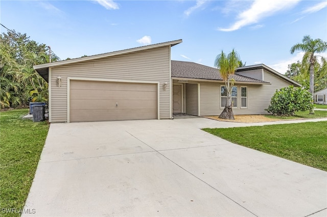 view of front of house featuring an attached garage, concrete driveway, a front lawn, and a shingled roof