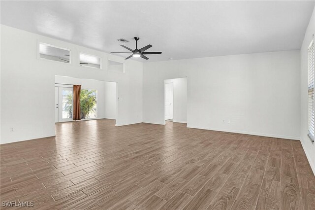 unfurnished living room with a ceiling fan, visible vents, and wood finished floors