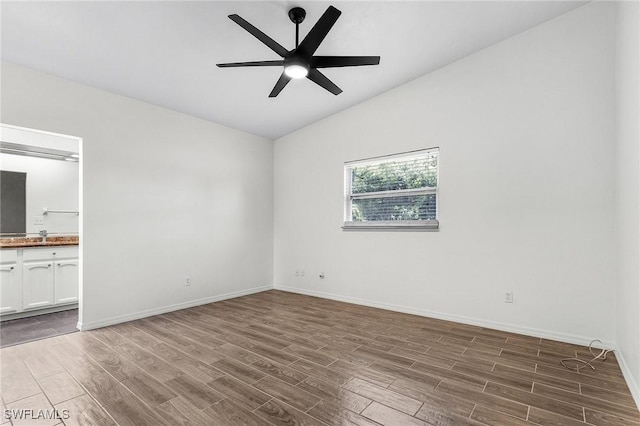 unfurnished room with ceiling fan, vaulted ceiling, baseboards, and wood finished floors