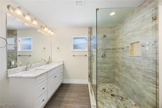 bathroom featuring double vanity, a stall shower, a sink, and visible vents