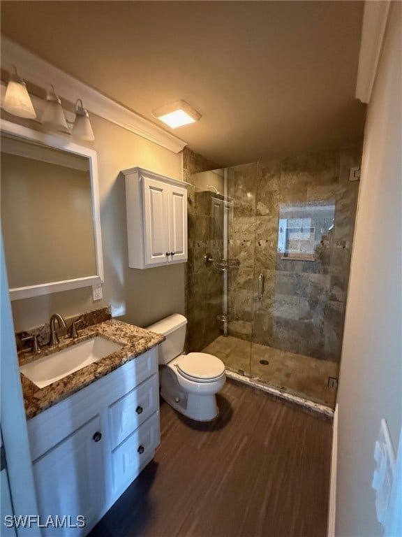 full bathroom featuring toilet, a stall shower, wood finished floors, and vanity