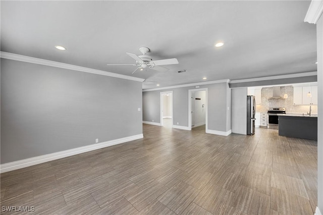 unfurnished living room with recessed lighting, a sink, a ceiling fan, and baseboards