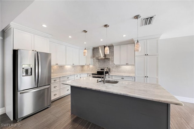 kitchen with tasteful backsplash, visible vents, wall chimney exhaust hood, appliances with stainless steel finishes, and a sink