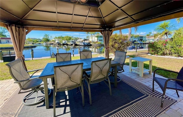 view of patio / terrace with a gazebo, outdoor dining space, a water view, and fence