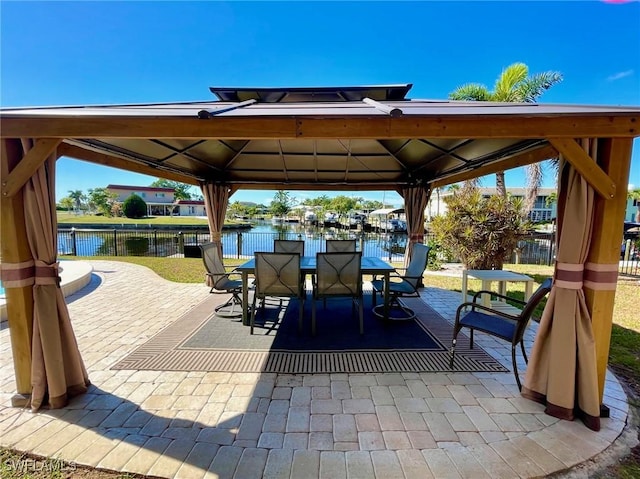 view of patio / terrace with a gazebo, outdoor dining area, a water view, and fence