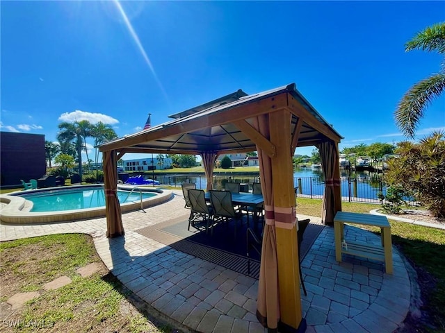 community pool with a gazebo, a patio, a water view, and fence