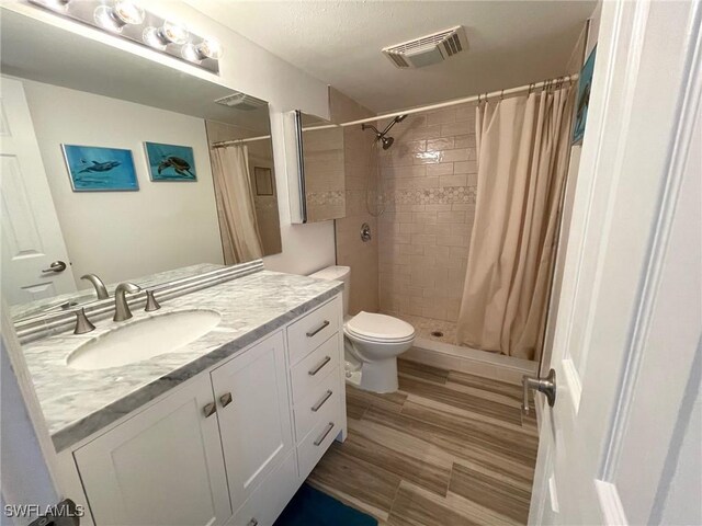 bathroom featuring visible vents, toilet, vanity, and a shower stall