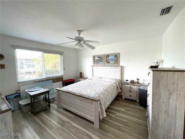 bedroom with ceiling fan, wood finished floors, and visible vents