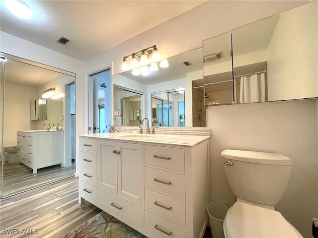 bathroom featuring toilet, visible vents, wood finished floors, and a shower with shower curtain