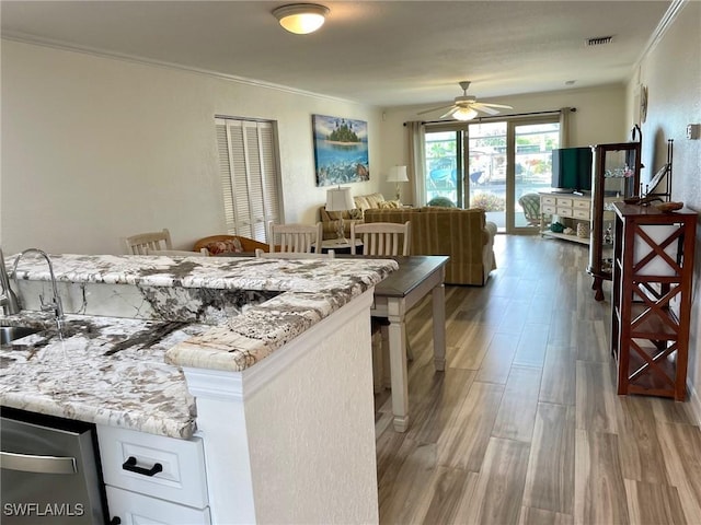 kitchen with visible vents, ornamental molding, a sink, and wood finished floors