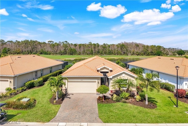 ranch-style home featuring a garage, decorative driveway, a front yard, and a tile roof