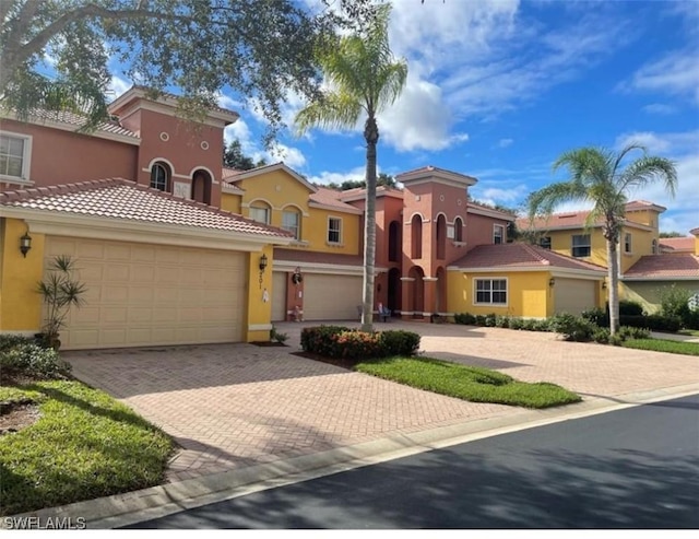 mediterranean / spanish-style home featuring stucco siding, a tile roof, and decorative driveway